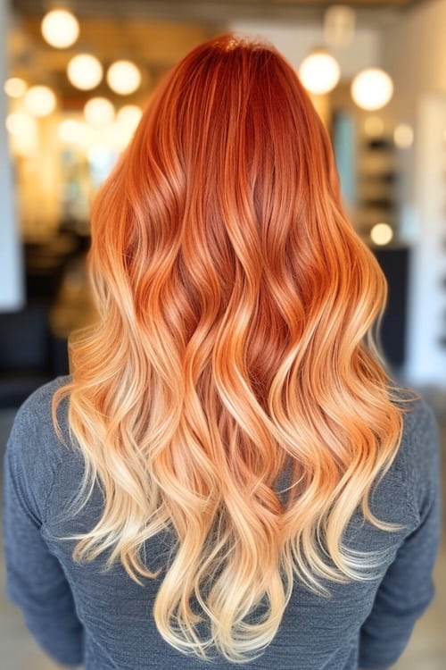 Fiery red long ombre waves on woman in hair salon, shot from back.