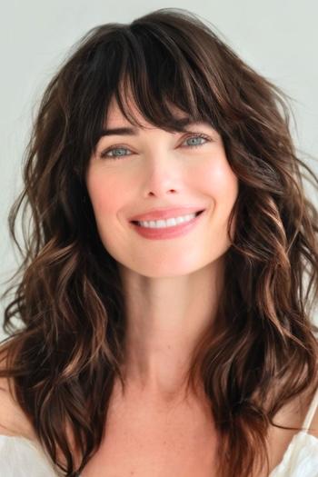 Layered Waves with Bangs Hairstyle on a smiling woman with brown hair.