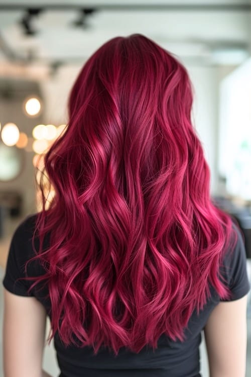 Raspberry red hair color on long wavy hair, shot from back.