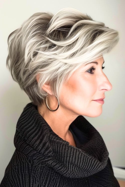 Voluminous pixie with platinum highlights short hairstyle on older woman.