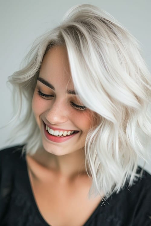 White blond shoulder-length hair on smiling woman looking down.