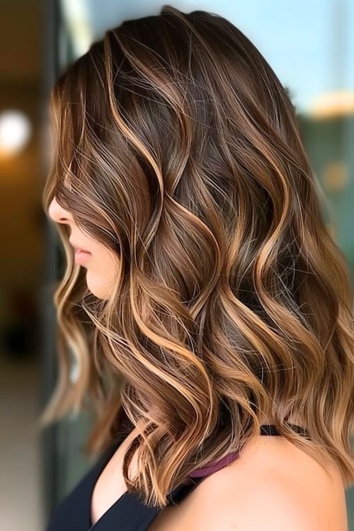 Caramel strawberry highlights on chestnut brown hair.