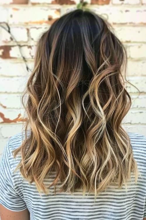 Dark brown wavy hair with butter blonde highlights.