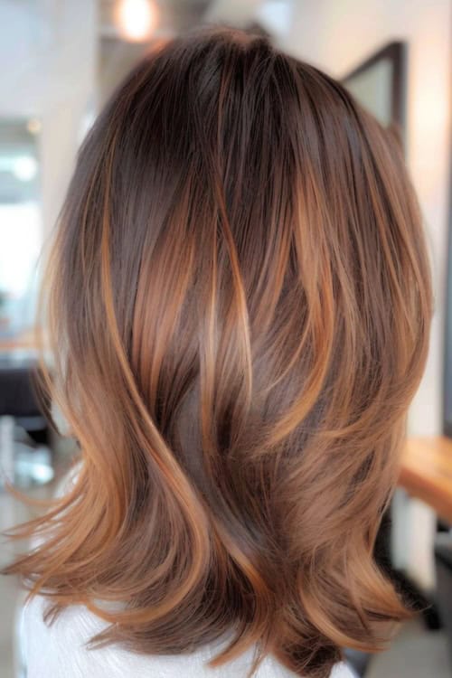 Layered caramel highlights on shoulder-length hair.