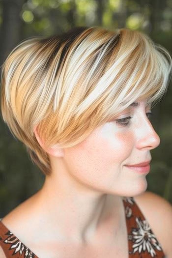 Blonde Pixie Bob with Dark Roots Haircut on a smiling woman with blonde hair, side view.