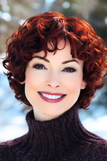 Deep Crimson Curly Layered Bob Hairstyle on a smiling woman with short deep coppery crimson hair.