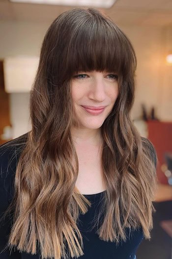 Long Blunt Waves With Full Bangs Hairstyle on a smiling woman with long brown hair.