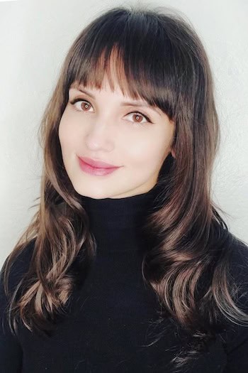 Long Layers With Wispy Bangs Hairstyle on a smiling woman with long brown hair.