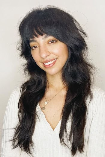 Long Shaggy Layers With Bangs Hairstyle on a smiling woman with long dark brown hair.