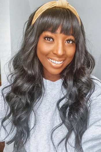 Long Soft Curls With Blunt Bangs Hairstyle on a smiling woman with long dark brown/black hair.