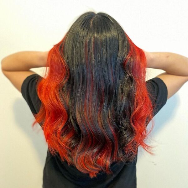 A woman back's view wearing her black top and with her finished red and black combo hair color