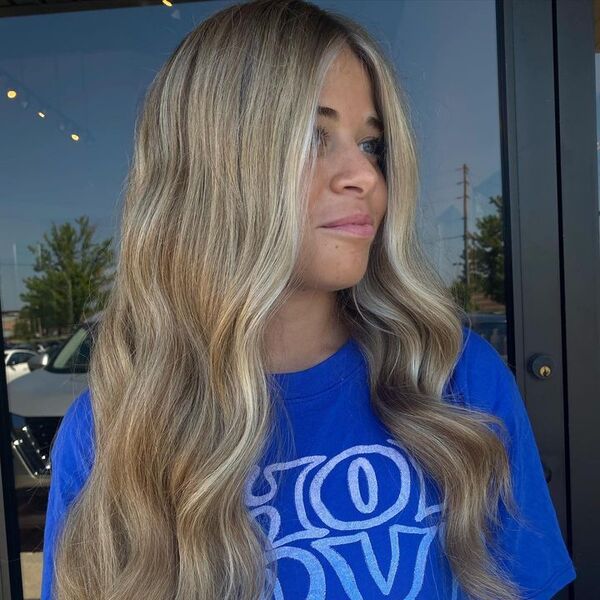 a woman outside wearing a blue printed shirt having her beige blonde hair with waves