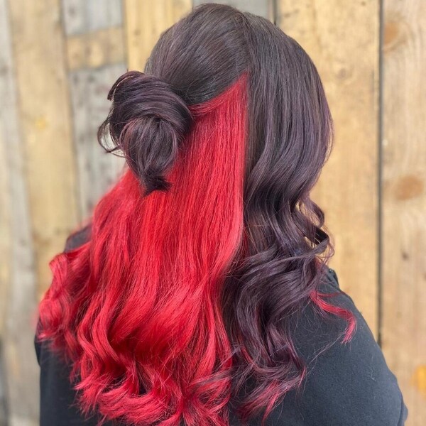 A woman with bun hair wearing black jacket having her red peekaboo black bun hair