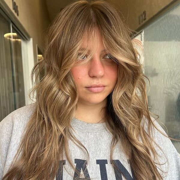 a woman with curtain bangs hair wearing a gray printed shirt