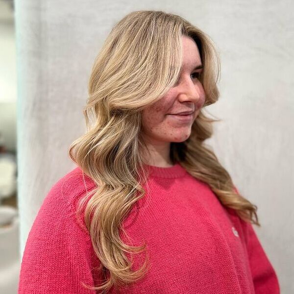 a woman with honey blonde hair wearing a dark pink knitted longsleeve