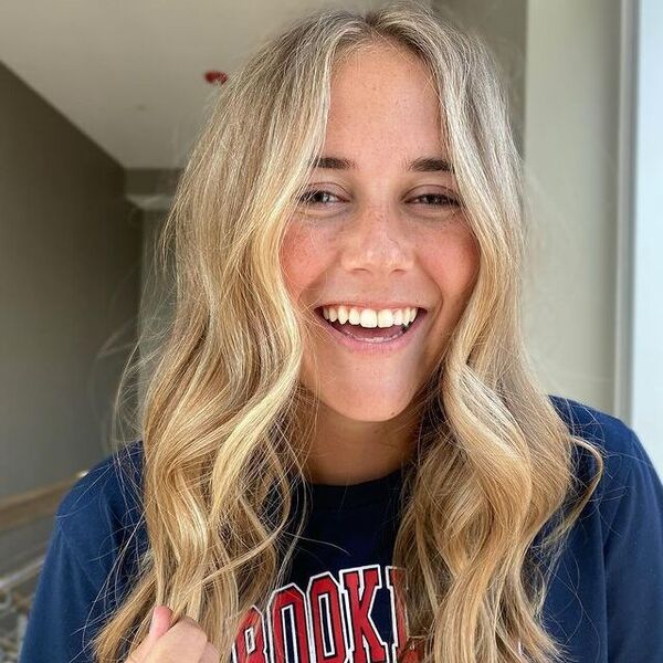 a woman with light blonde hair wearing a dark blue printed shirt