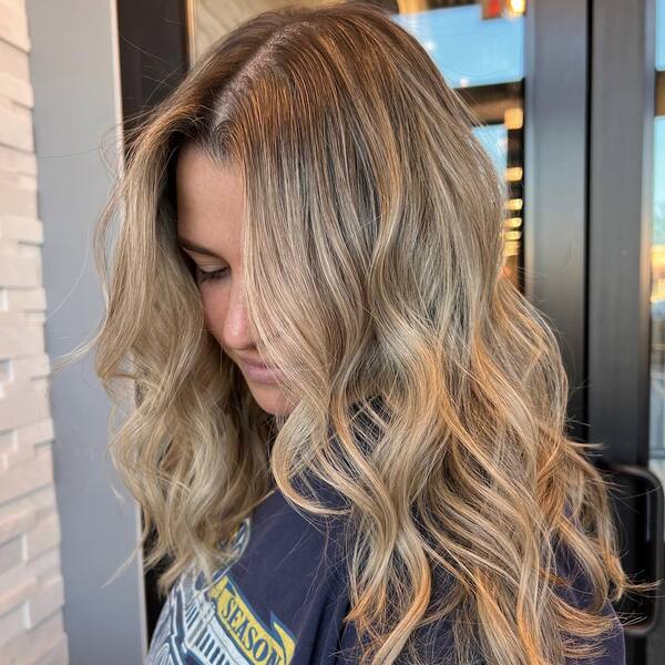 a woman with rooted blonde hair wearing a black printed shirt