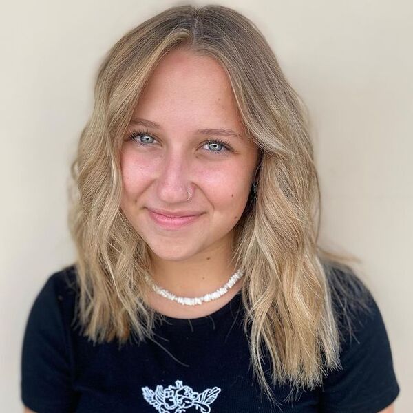 a woman with white chooker necklace wearing a black printed top having her subtle light brown hair