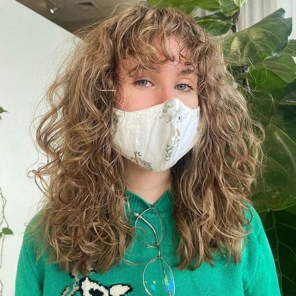 a woman with white printed facemask wearing a green knitted longsleeve