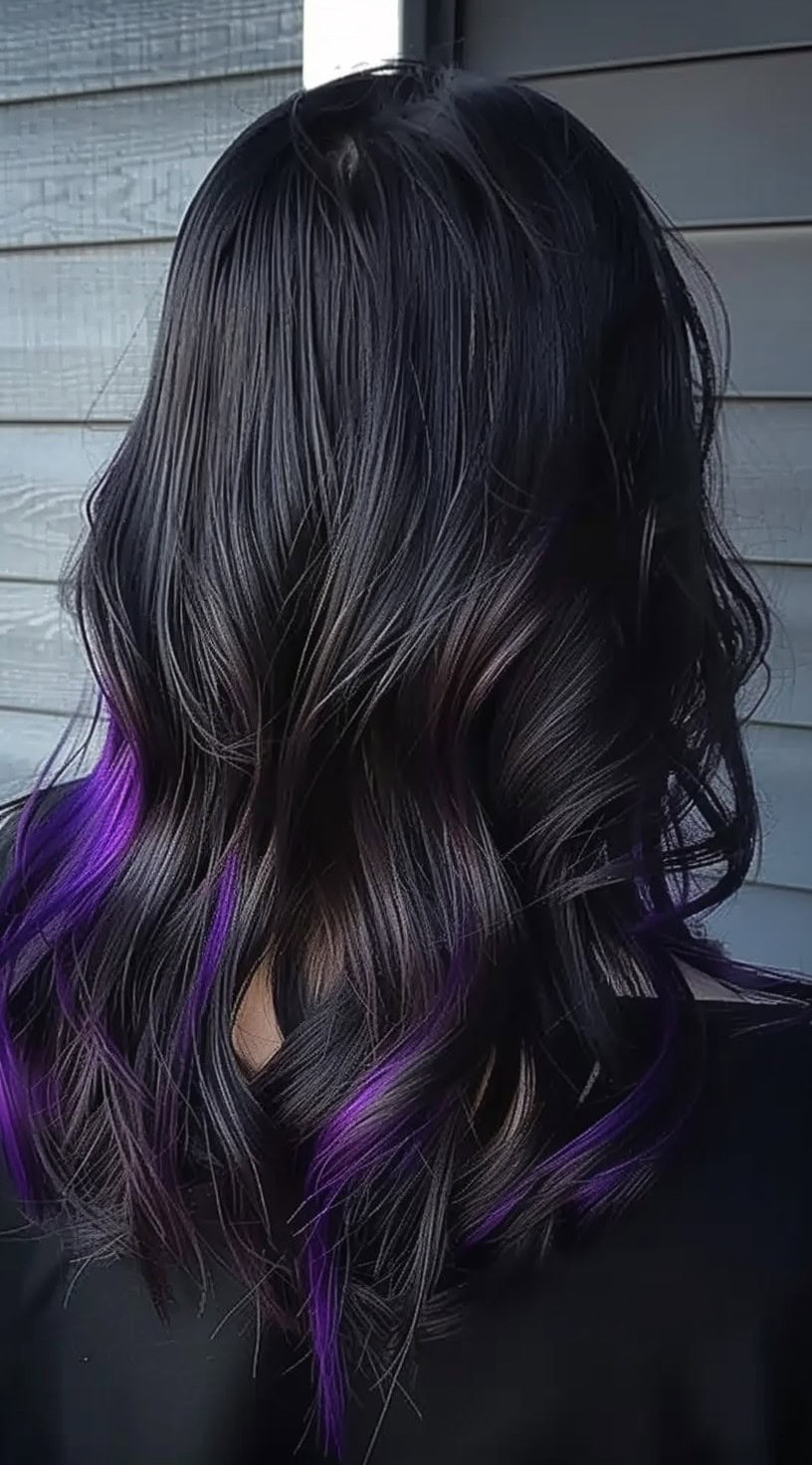 Back view of dark hair with vibrant purple highlights subtly peeking through the wavy layers.