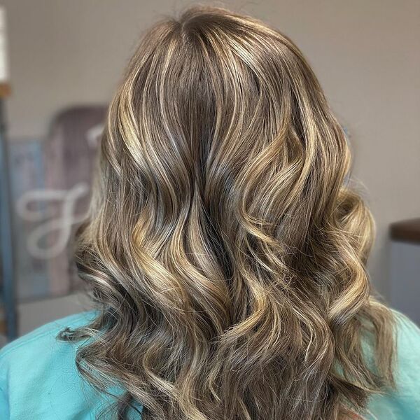 Beautiful Wavy Blonde Balayage - a woman wearing a blue green shirt