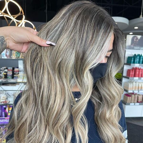 Champagne Blonde Balayage - a woman in a salon wearing a black facemask