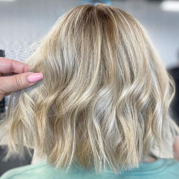 Color Melt Platinum Blonde - a woman wearing a green shirt and a hand is holding her hair