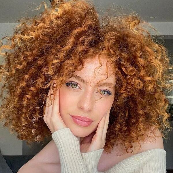 Copper Strawberry Blonde Hair with Afro Curls - a woman wearing a creamy white longsleeve