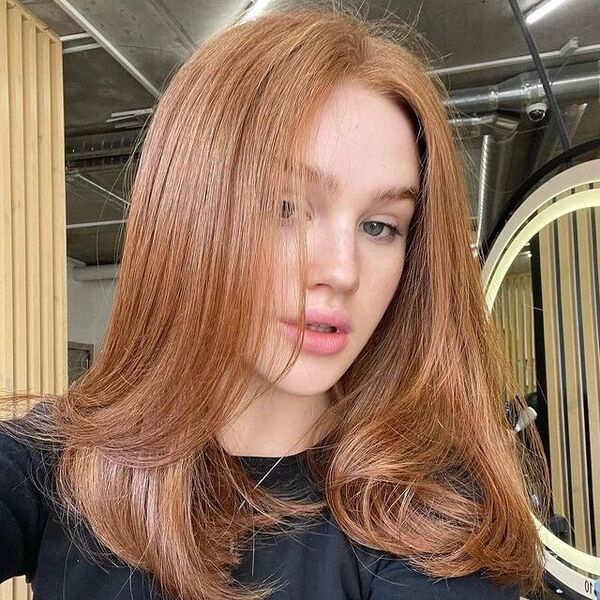 Copper Strawberry Blonde Hair with Layers - a woman wearing a black longsleeve