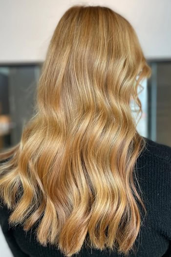 Golden Apricot Blonde Waves on a woman with long blonde wavy hair, back view.