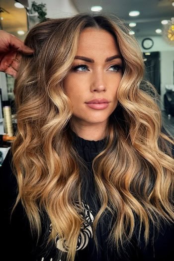 Golden Caramel Blonde Balayage hair color on a woman with long wavy blonde hair.