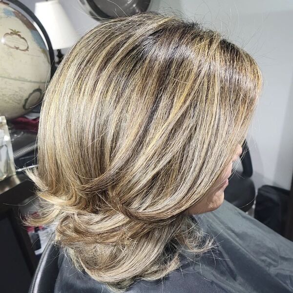 Layered Hair with Light Brown Balayage - a woman wearing a black cape in a salon