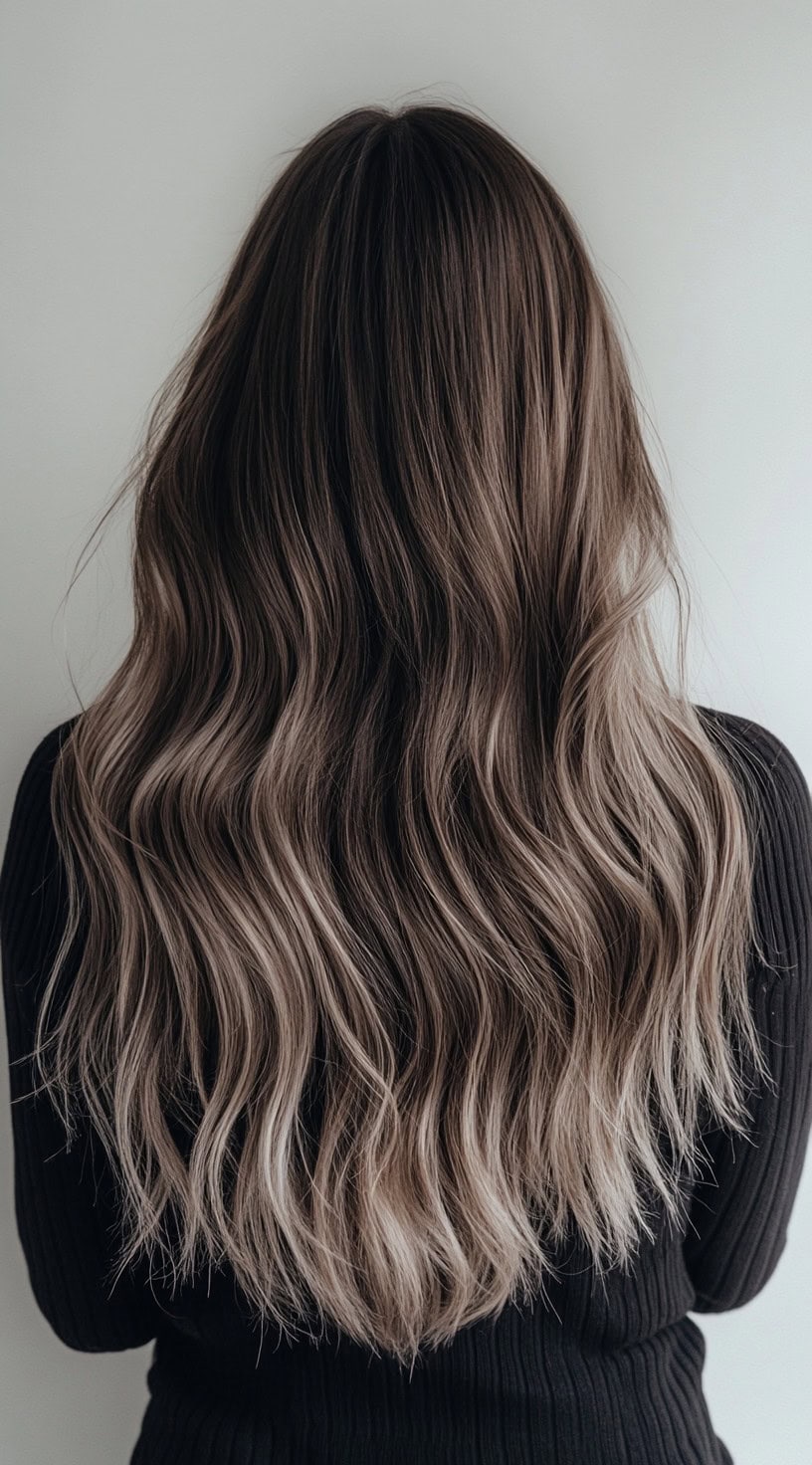 Long brunette hair with cool beige blonde balayage and soft waves.