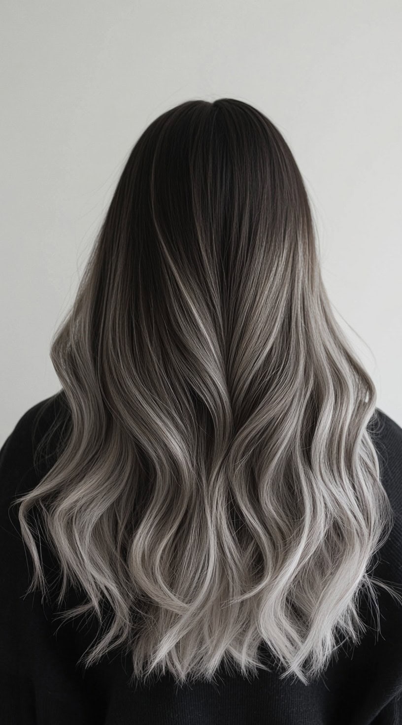 Long, wavy hair with dark roots transitioning into cool, icy blonde balayage.