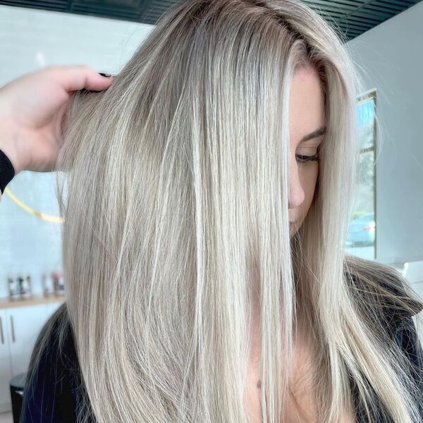 Mint Blonde Balayage - a woman in a salon wearing a black jacket