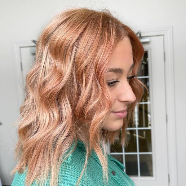 Pink Strawberry Blonde Hair - a woman wearing a green top