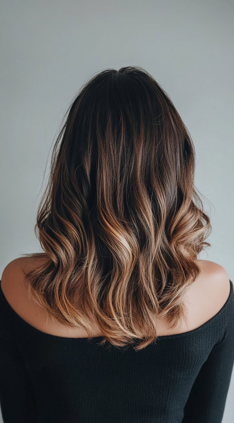 Shoulder-length brunette hair with caramel blonde balayage and soft curls.