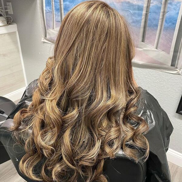 Spring Hair with Full Headlights - a woman sitting in a salon chair and is wearing a cape