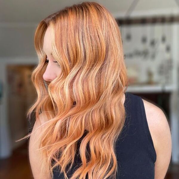 Strawberry Blonde Hair with Highlights - a woman wearing a black sleeveless shirt