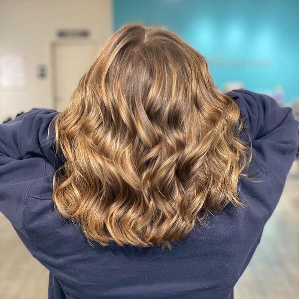 Sunkissed Light Brown Balayage - a woman wearing a dark blue jacket