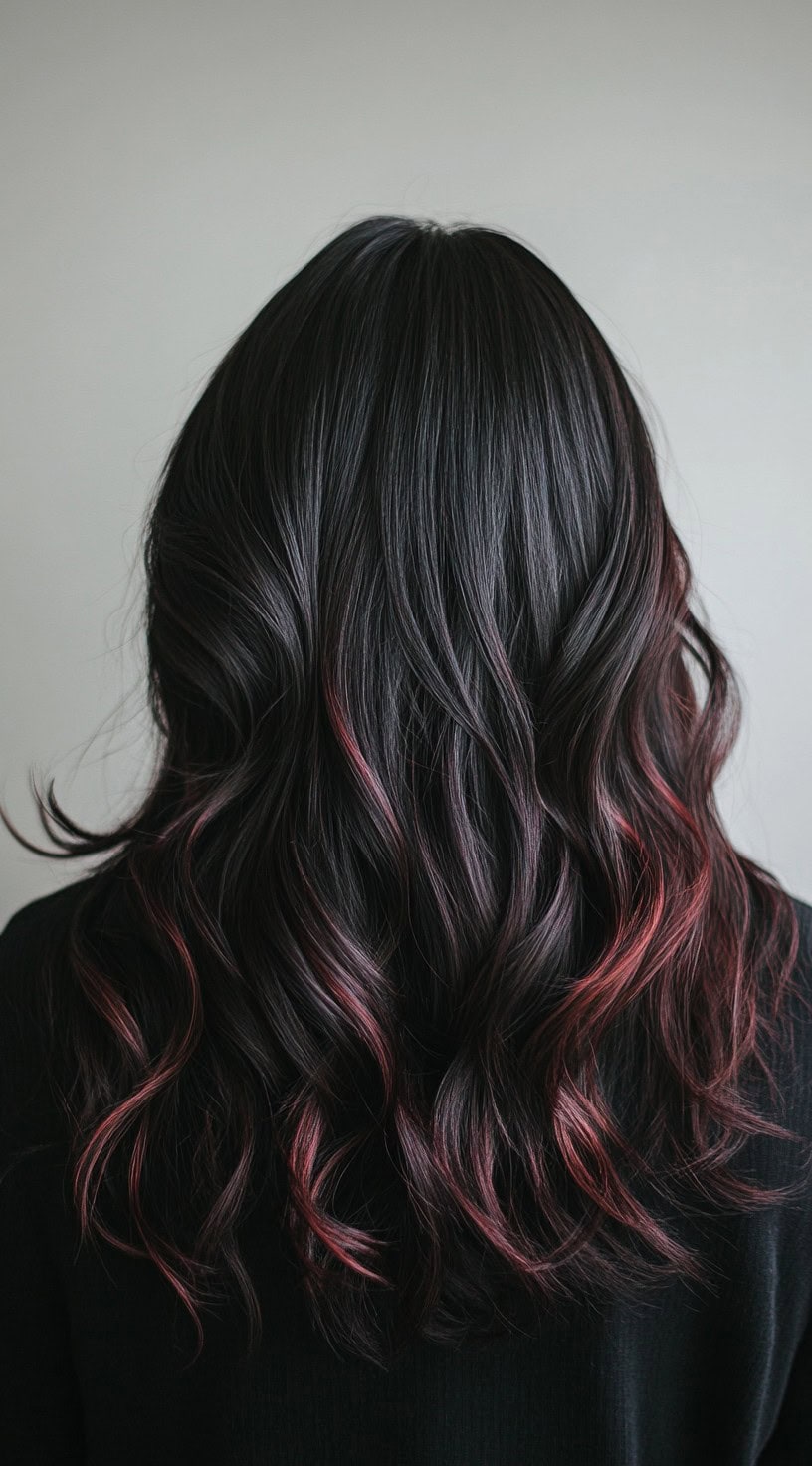 The photo presents loose, voluminous waves with deep red highlights delicately threaded through the black base.