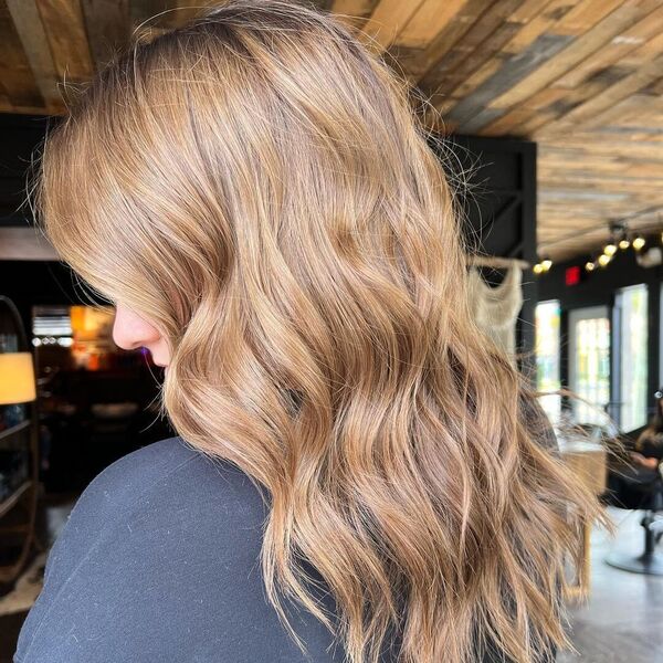 Trendy Light Brown Balayage - a woman in a salon wearing a black shirt