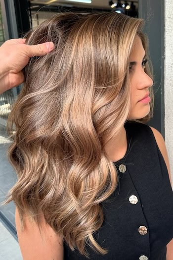 Warm Blonde Balayage on Brown Hair on a woman with brown hair and blonde balayage highlights.