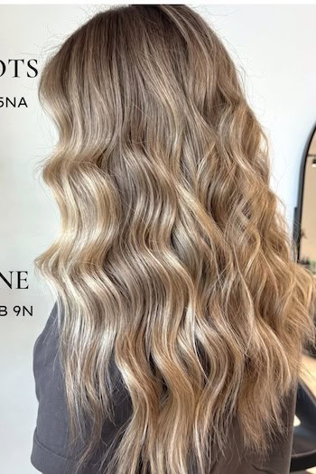 Warm Blonde Balayage On Long Hair on a woman with long blonde hair, side view.