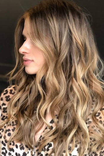 Warm Bronde Waves with Dark Roots for Autumn on a woman with blonde hair, side view.