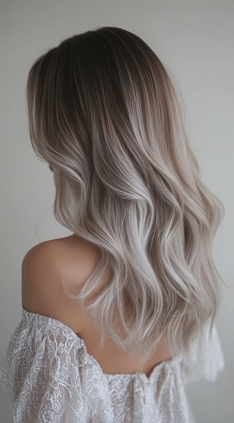 Wavy, shoulder-length hair with dark roots transitioning into cool ash blonde balayage.